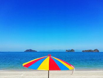 Multi colored umbrellas on beach against clear blue sky