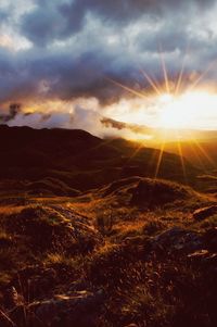 Scenic view of mountains against cloudy sky at sunrise