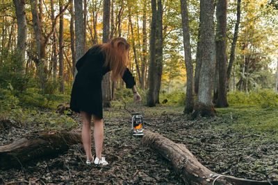 Full length of woman with oil lamp standing in forest