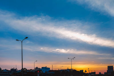 Low angle view of street and buildings against sky during sunset