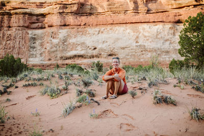 Woman sitting on sand dune in a desert smiles at camera in the maze