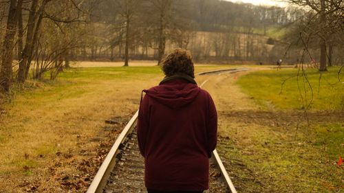 Rear view of woman standing on railroad track in forest