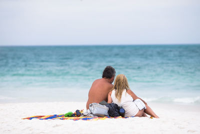 Rear view of men sitting on beach