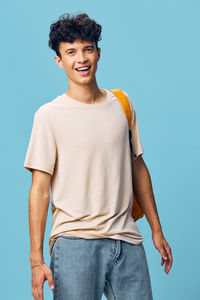 Portrait of young man standing against blue background