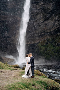 Woman standing against waterfall