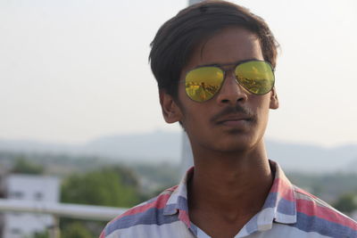 Portrait of young man wearing sunglasses against sky