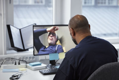 Male doctor having online consultation with senior patient