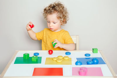 Toddler baby playing sorting organising objects blocks with specific colors. early age education. 