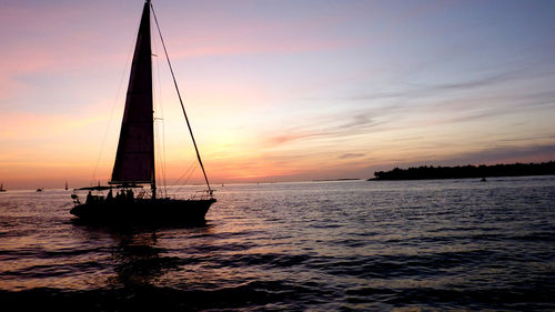 Silhouette sailboat sailing on sea against sky during sunset