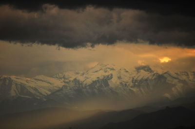 Scenic view of snowcapped mountains against dramatic sky