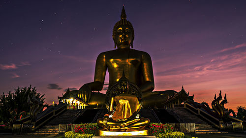 Low angle view of golden buddha statues against star field