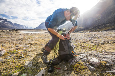 Backpacker works hard to fit all his gear inside his backpack.