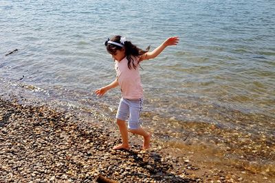 Full length of girl with arms outstretched walking at shore