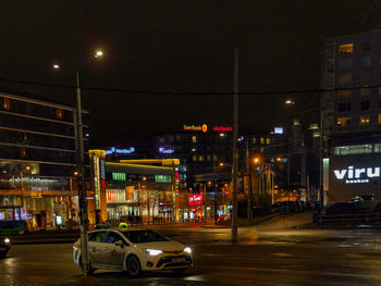 Cars on illuminated road against sky at night