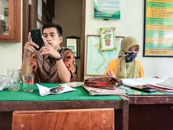 Young man using smart phone while sitting in restaurant