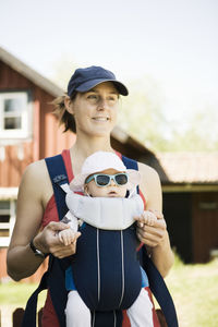 Mother standing with baby in carrier