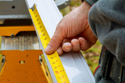 Cropped image of man measuring molding with tape measure