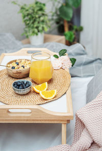 Healthy breakfast. orange juice, fruits and bowl with granola on a tray. breakfast in bed.