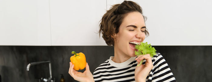 Portrait of young woman holding food at home