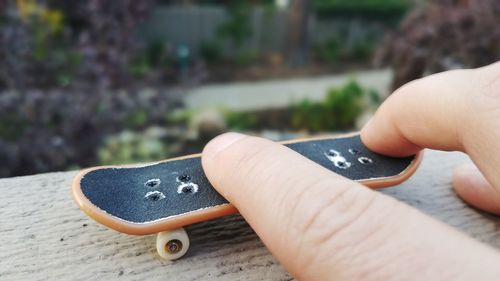 Cropped hand playing with toy skateboard on table