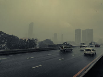 Cars on road in city against sky