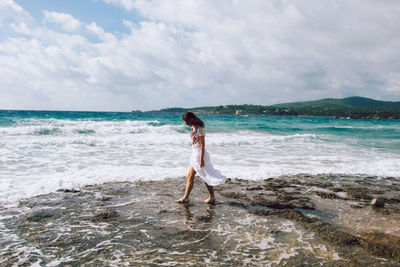 Woman wading in sea against sky