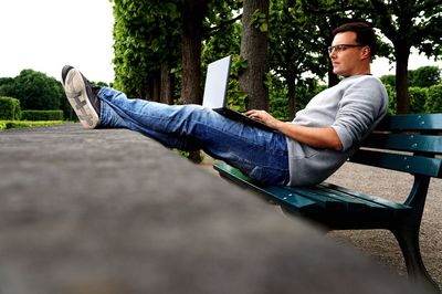 Man using laptop while sitting on bench in park