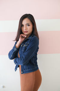 Portrait of beautiful young woman standing against wall