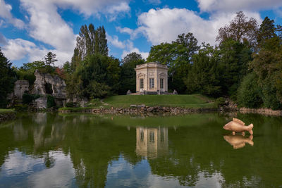 Reflection of building in lake against cloudy sky