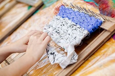 High angle view of person hands making rug on table