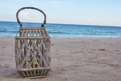 Wooden lantern on beach against blue sky