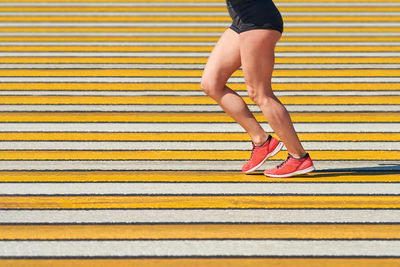 Woman running crosswalk, copy space. athletic woman jogging in sportswear on city road