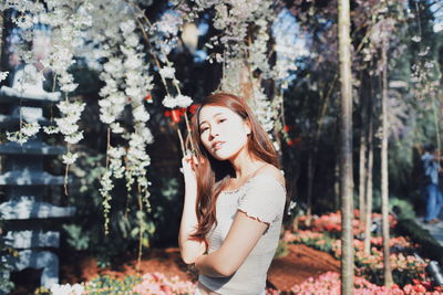 Portrait of young woman standing against plants in park