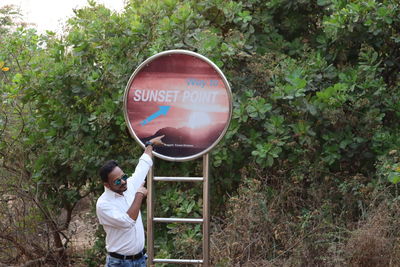 Rear view of man holding balloon standing against trees