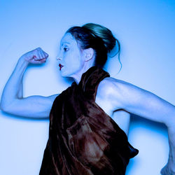 Woman flexing muscle against wall
