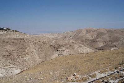 Scenic view of arid landscape against clear blue sky