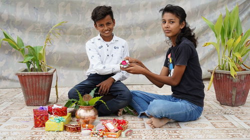 Happy sister looking at the camera while tying rakhi and received gifts. occasion of raksha bandhan