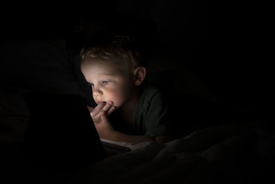 Portrait of boy using mobile phone in bed