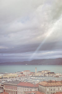 Cityscape by sea against sky