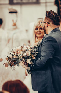 Man talking with woman while holding bouquet