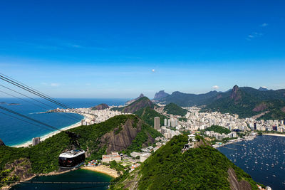 High angle view of city by sea against blue sky