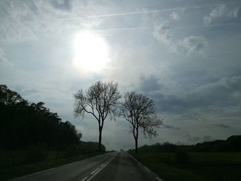 Road by trees against sky