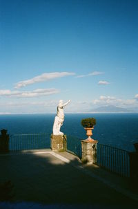 Statue by sea against blue sky