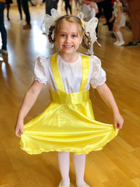 Portrait of young girl in yellow dress standing on floor