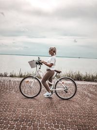 Side view of woman riding bicycle against sea