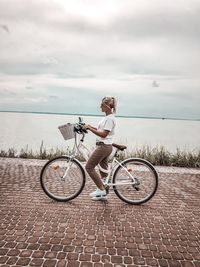 Bicycle parked by sea against sky