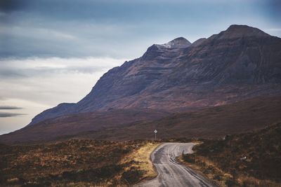 Road leading towards mountains against sky