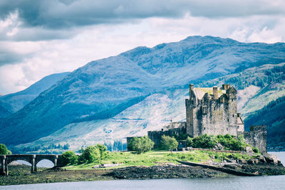 Scottish castle with bridge and scottish flag before mountains and sea