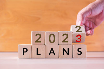 Cropped hand of person with toy blocks with text on table