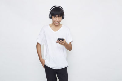 Young man using smart phone against white background